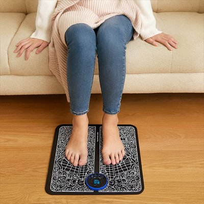 femme assise sur canape avec pieds sur appareil pour massage des pieds